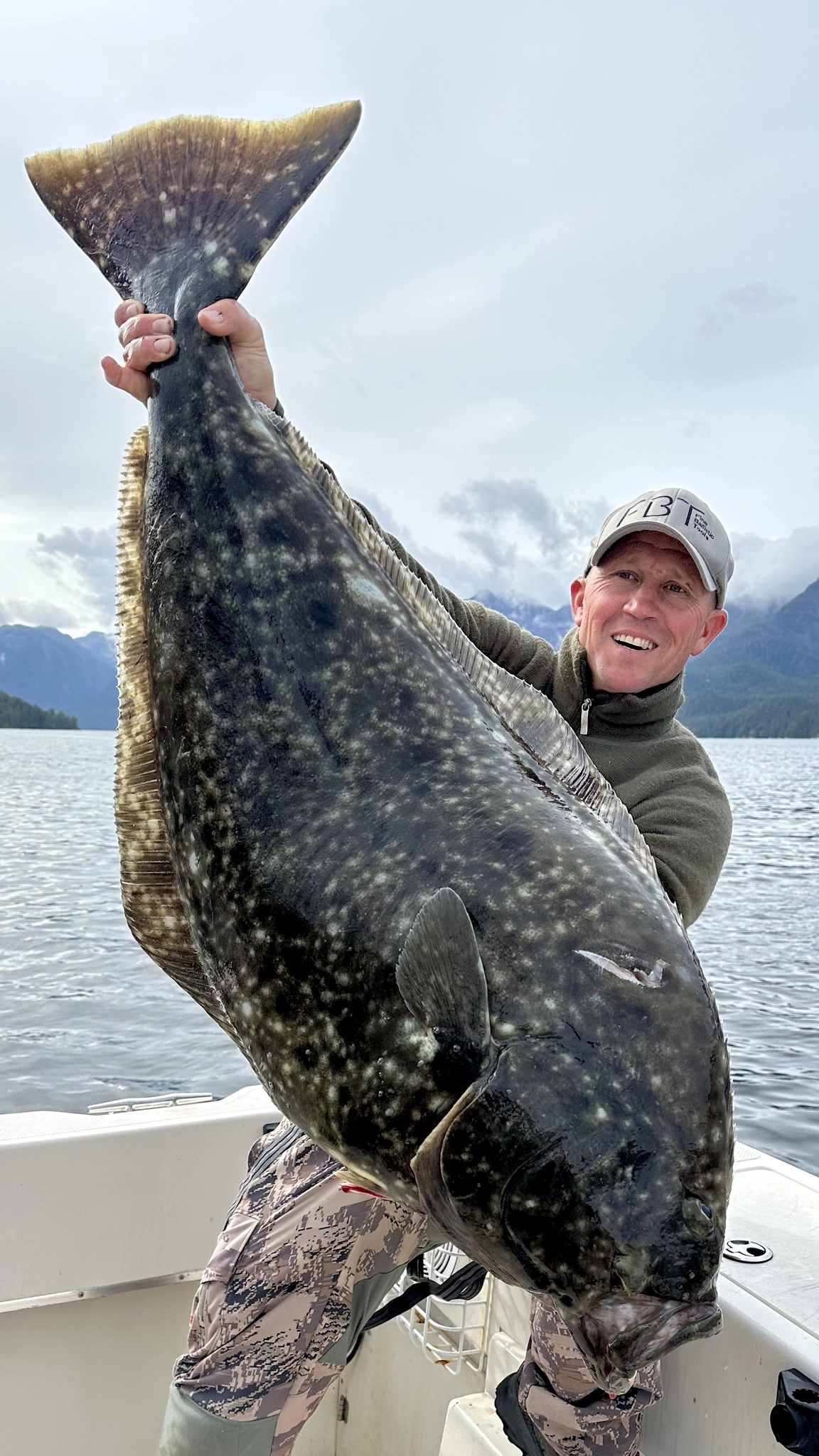 Angler holding an enormous halibut aboard a Blue Heron Charters fishing boat on the Douglas Channel near Kitimat, BC.